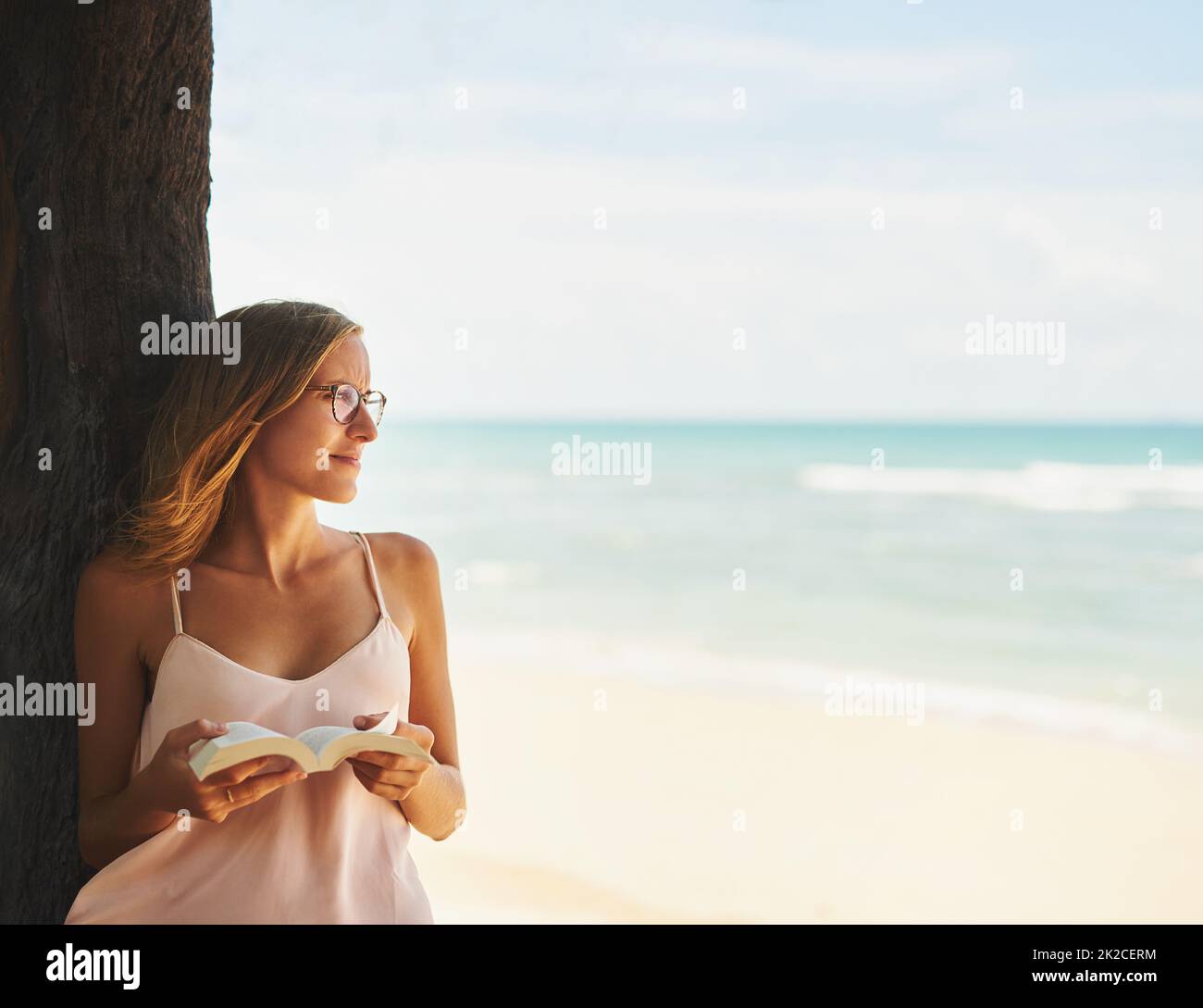 The beach is a place of serenity and quiet contemplation. Cropped shot of a young woman reading a book at the beach. Stock Photo