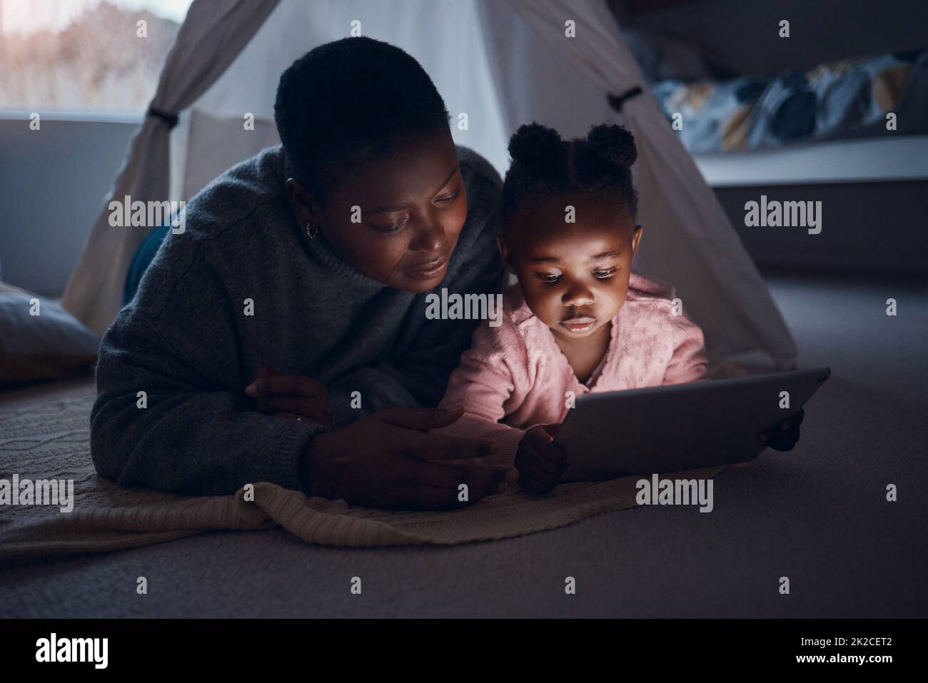 What are you going to read mom. Shot of a mother reading bedtime stories with her daughter on a digital tablet. Stock Photo