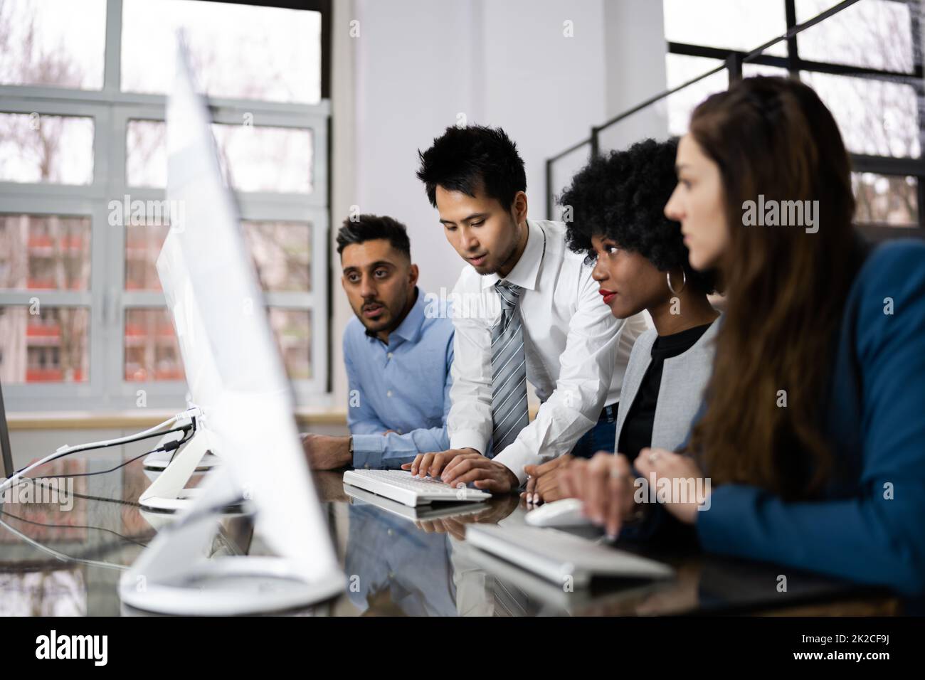 Happy Business People Using Laptop Discussing At Workplace Stock Photo