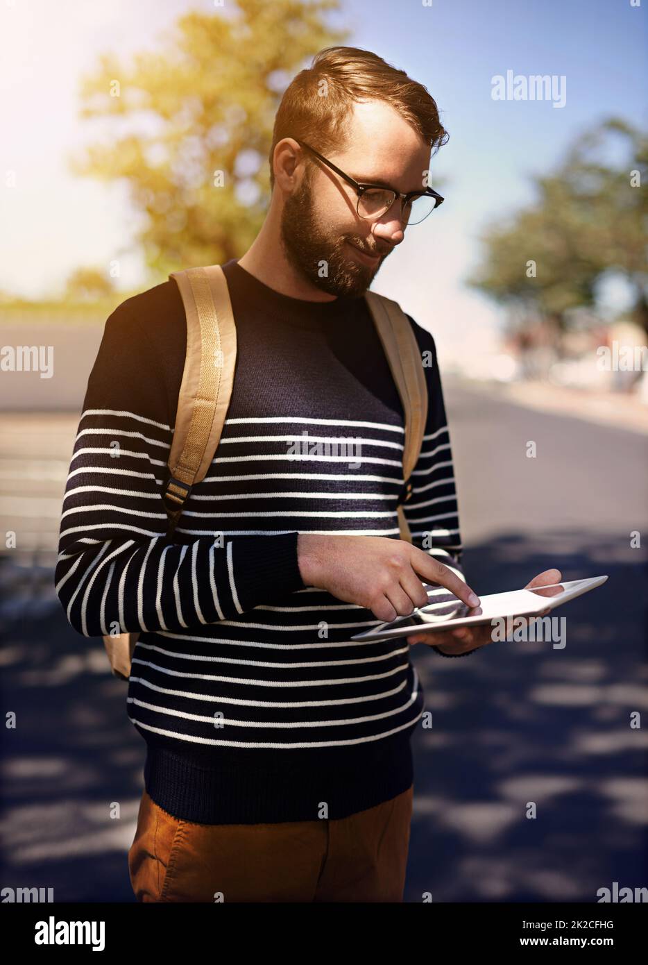 The smart traveler. Shot of a trendy young man using a digital tablet outdoors. Stock Photo