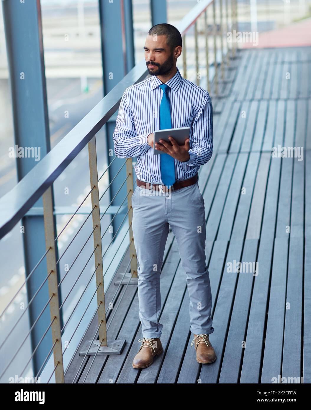 Technology brings business closer to him. Shot of a young businessman using a digital tablet outside of an office building. Stock Photo