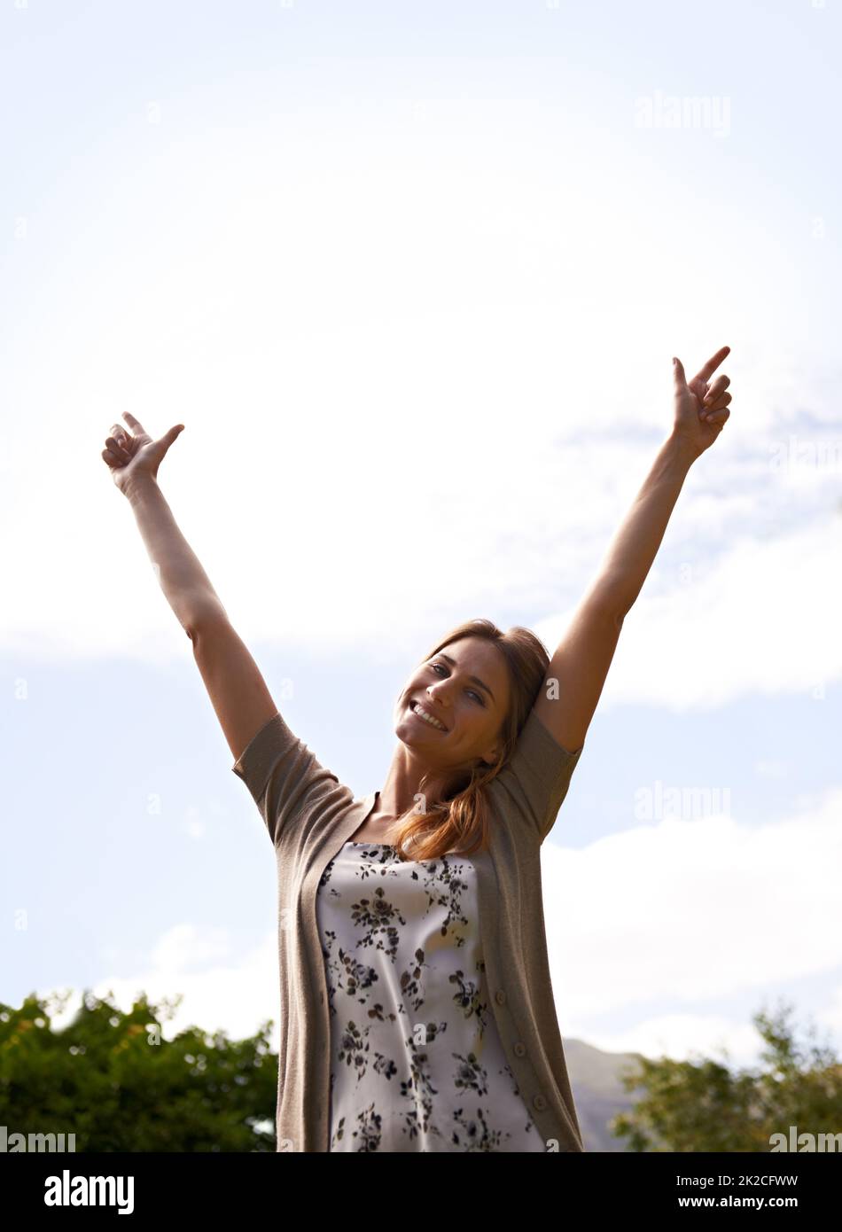 Raise your hands if you love freedom. Shot of a beautiful young woman with her arms raised outdoors. Stock Photo