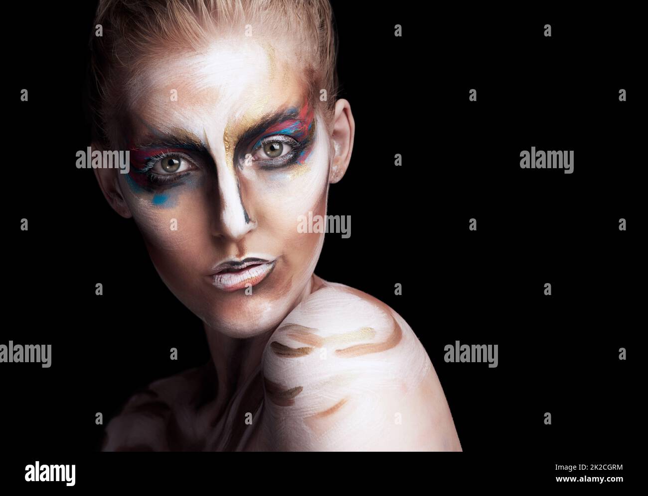 Confident in colour. Studio portrait of a young woman posing with paint on her face isolated on black. Stock Photo