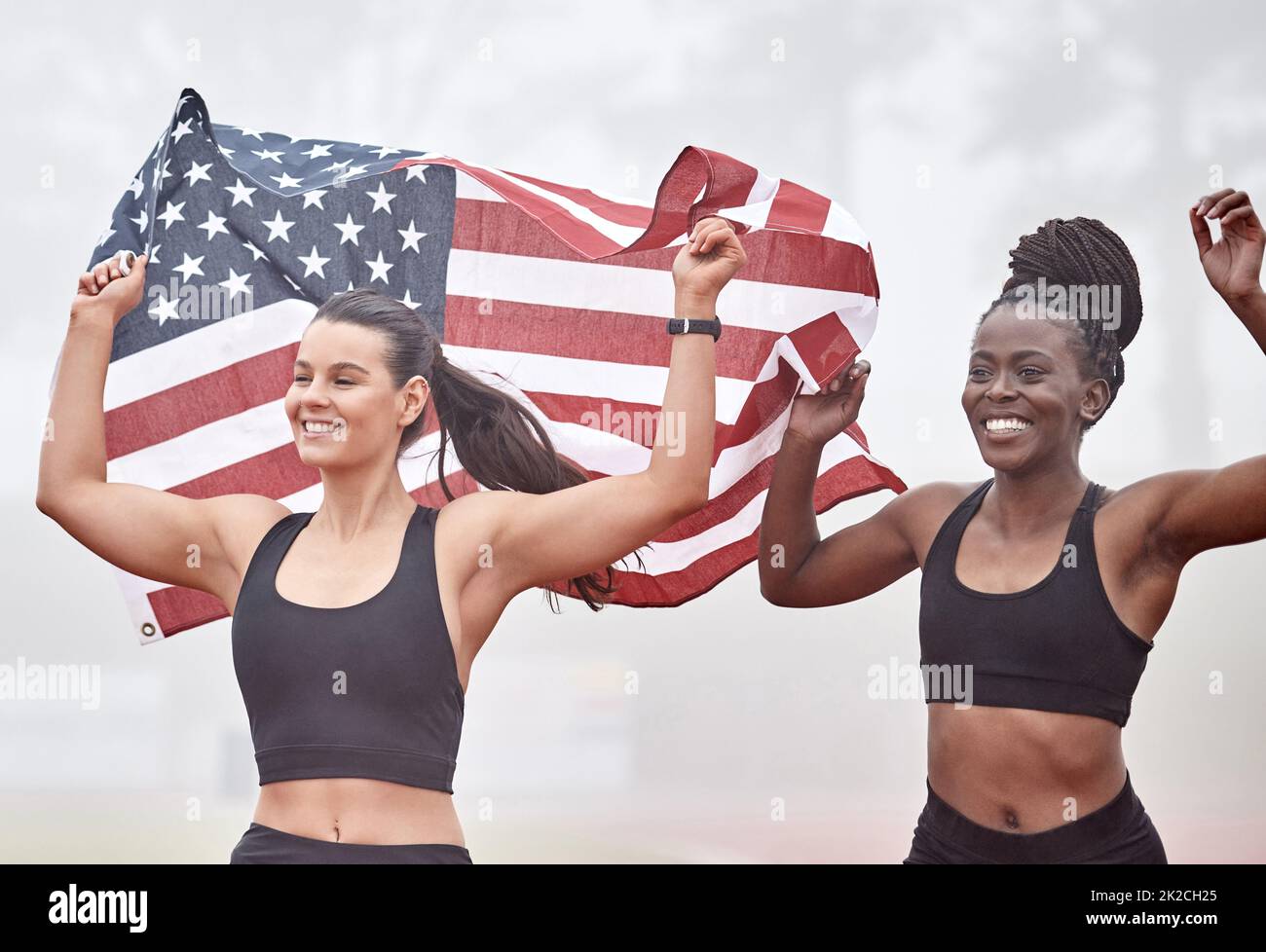 We did this for our country. Shot of female athletes celebrating their win while holding a flag. Stock Photo