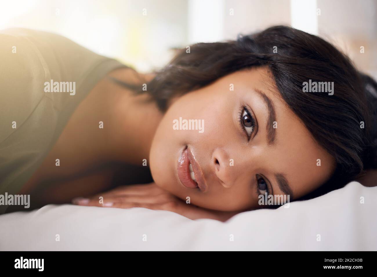 Time is precious, waste it wisely. Portrait of a young woman lying on her bed. Stock Photo