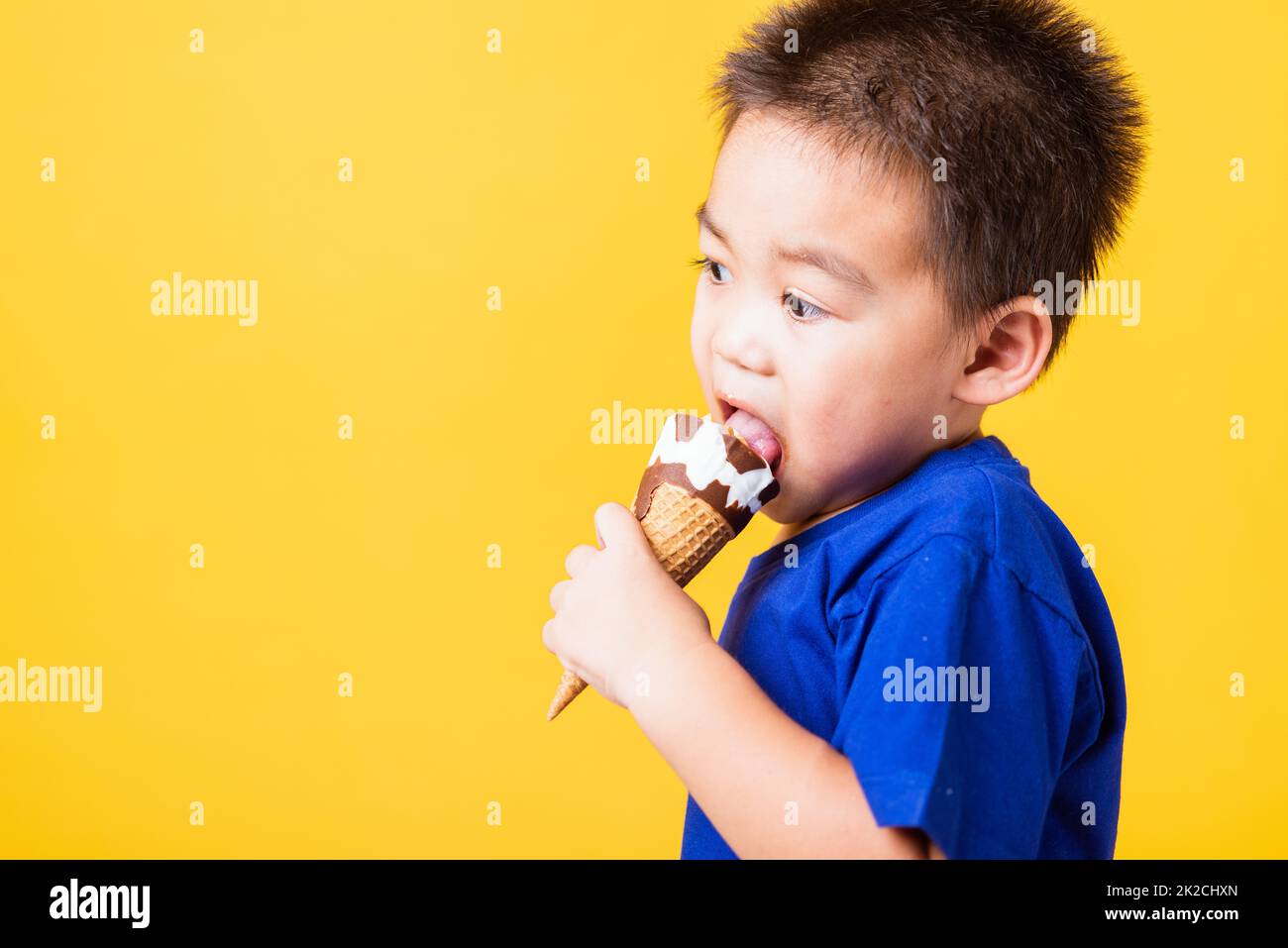 kid cute little boy attractive laugh smile playing holds and eating sweet chocolate ice cream waffle cone Stock Photo