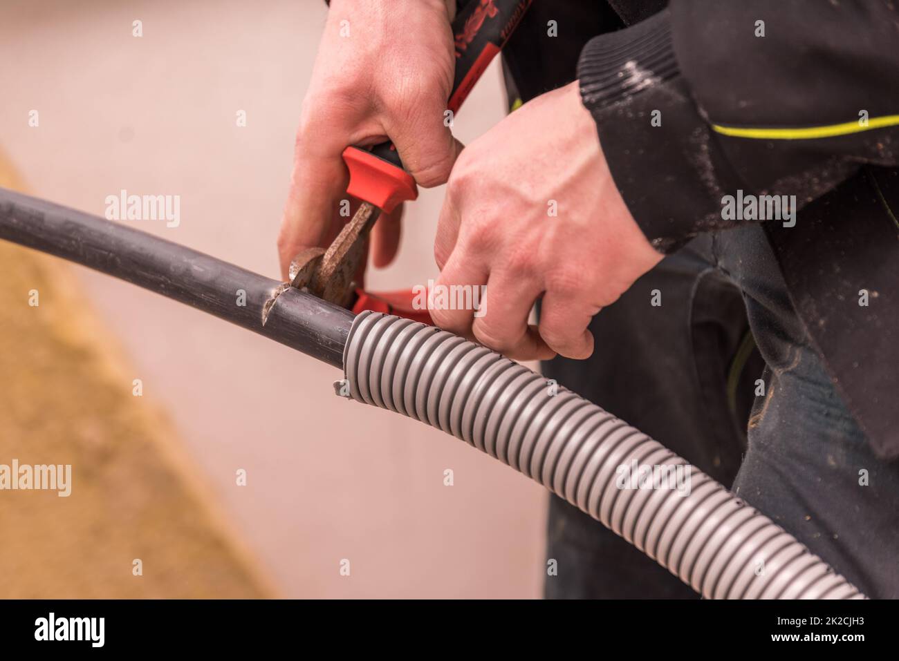 Electrician cuts with side cutters on underground cable insulation - power line Stock Photo