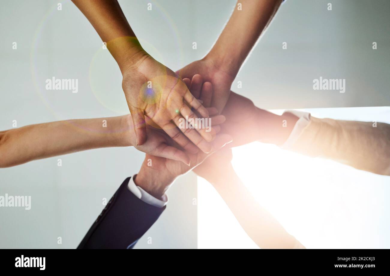 Share the goal, share the success. Low angle shot of a group of colleagues joining their hands in solidarity. Stock Photo