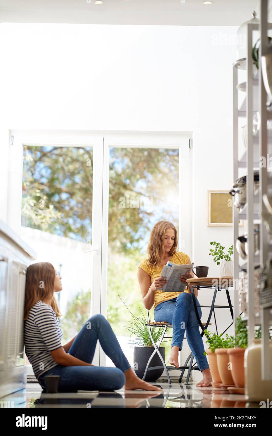 Catching up in the kitchen. twin sisters relaxing together in their