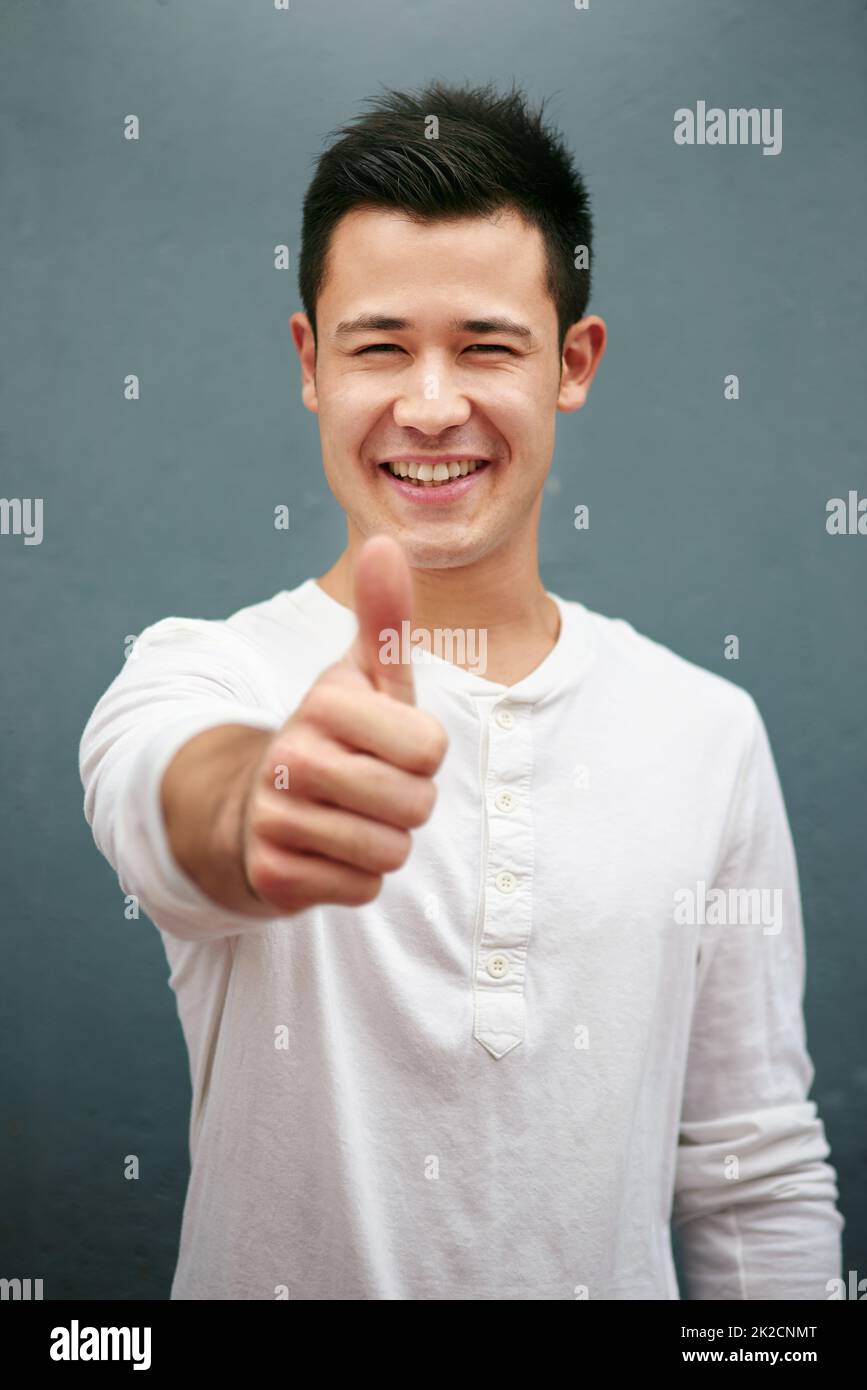 Hope youre having a great weekend. Studio portrait of a handsome young man showing thumbs up against a grey background. Stock Photo