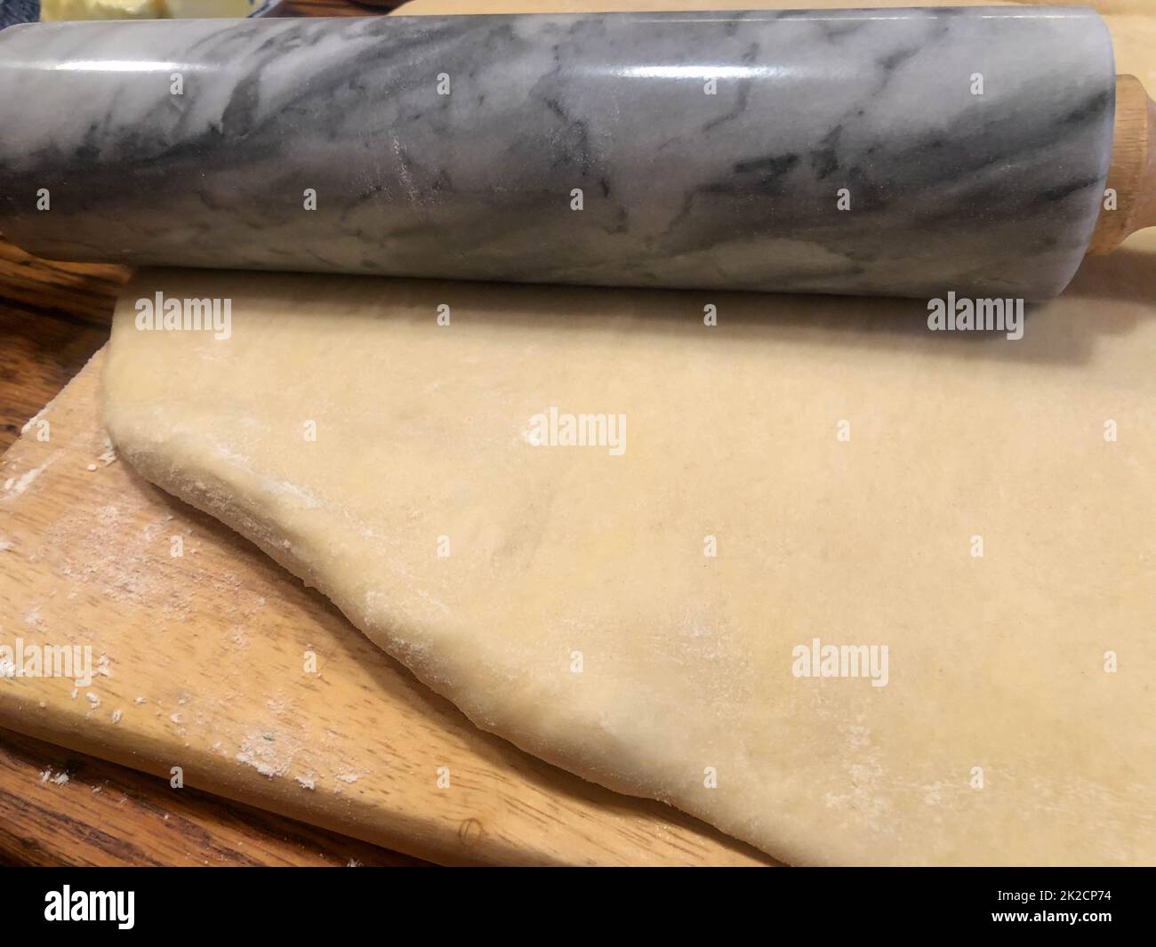 Wooden bakery counter with rolled dough and granite rolling pin Stock Photo