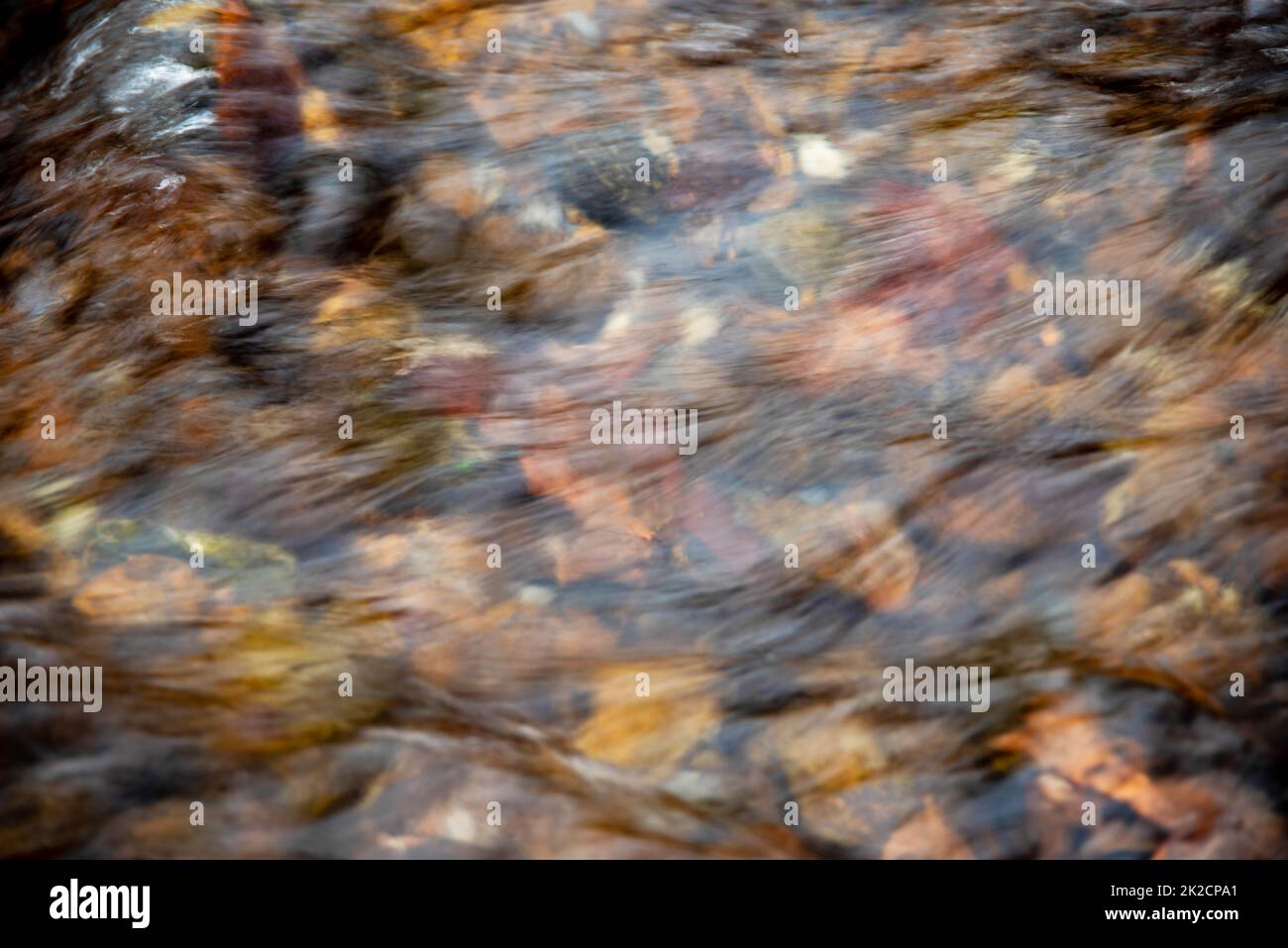 High angle view of shallow flowing stream over colorful stones Stock Photo