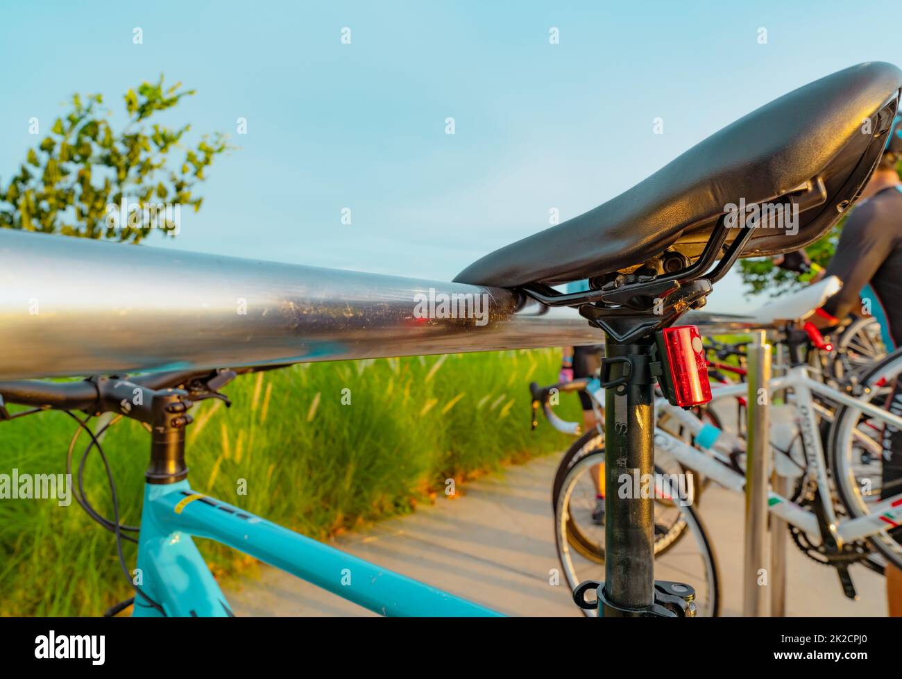 Bicycle parked on aluminium rack at the park. Outdoor exercise and recreation activity. Bicycle at bike parking station. Eco-friendly. Healthy lifestyle. Outdoor activity in summer. Extreme sport. Stock Photo