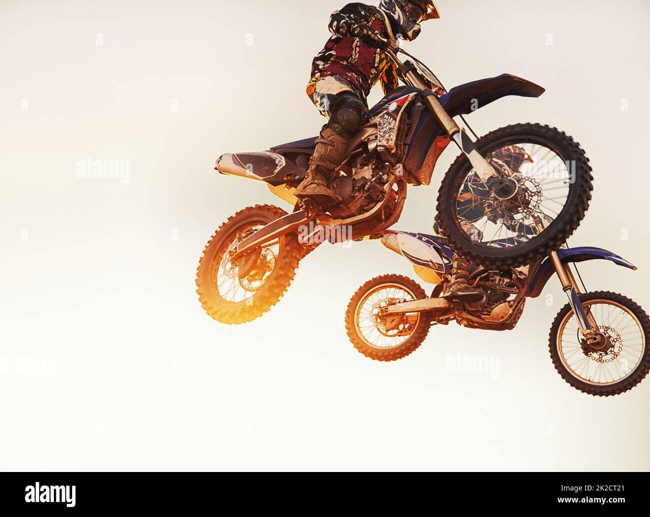 Theyre neck-a-neck. A shot of two motocross riders in midair during a race. Stock Photo