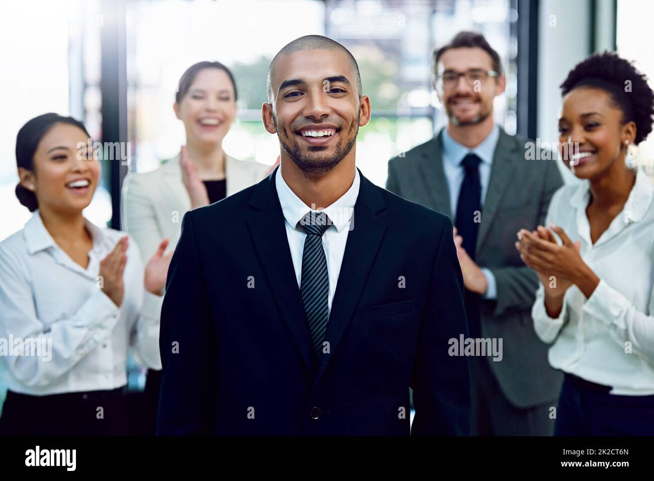 Another step up the corporate ladder. Portrait of a succesful businessman being applauded by his colleagues in the office. Stock Photo
