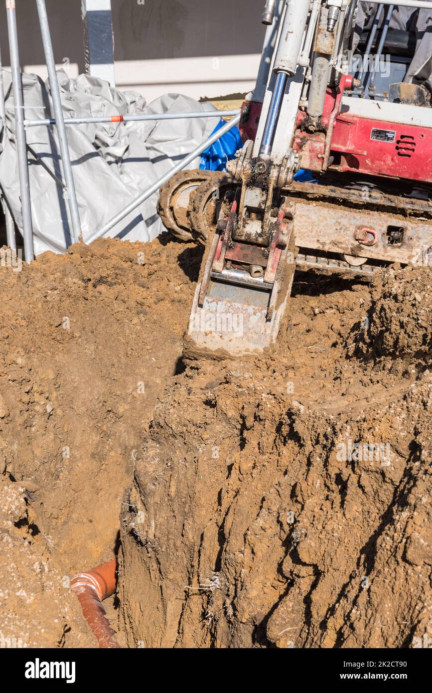 Excavations and earthworks on a construction site with a small excavator Stock Photo