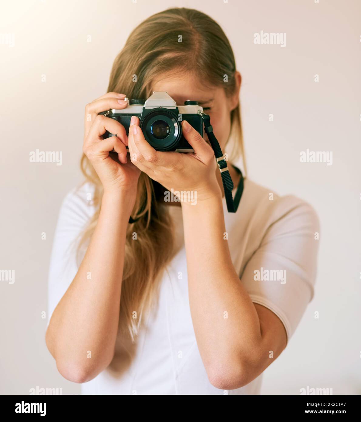Freezing this moment in time. Shot of an unrecognizable young woman taking a photo with her camera at home. Stock Photo