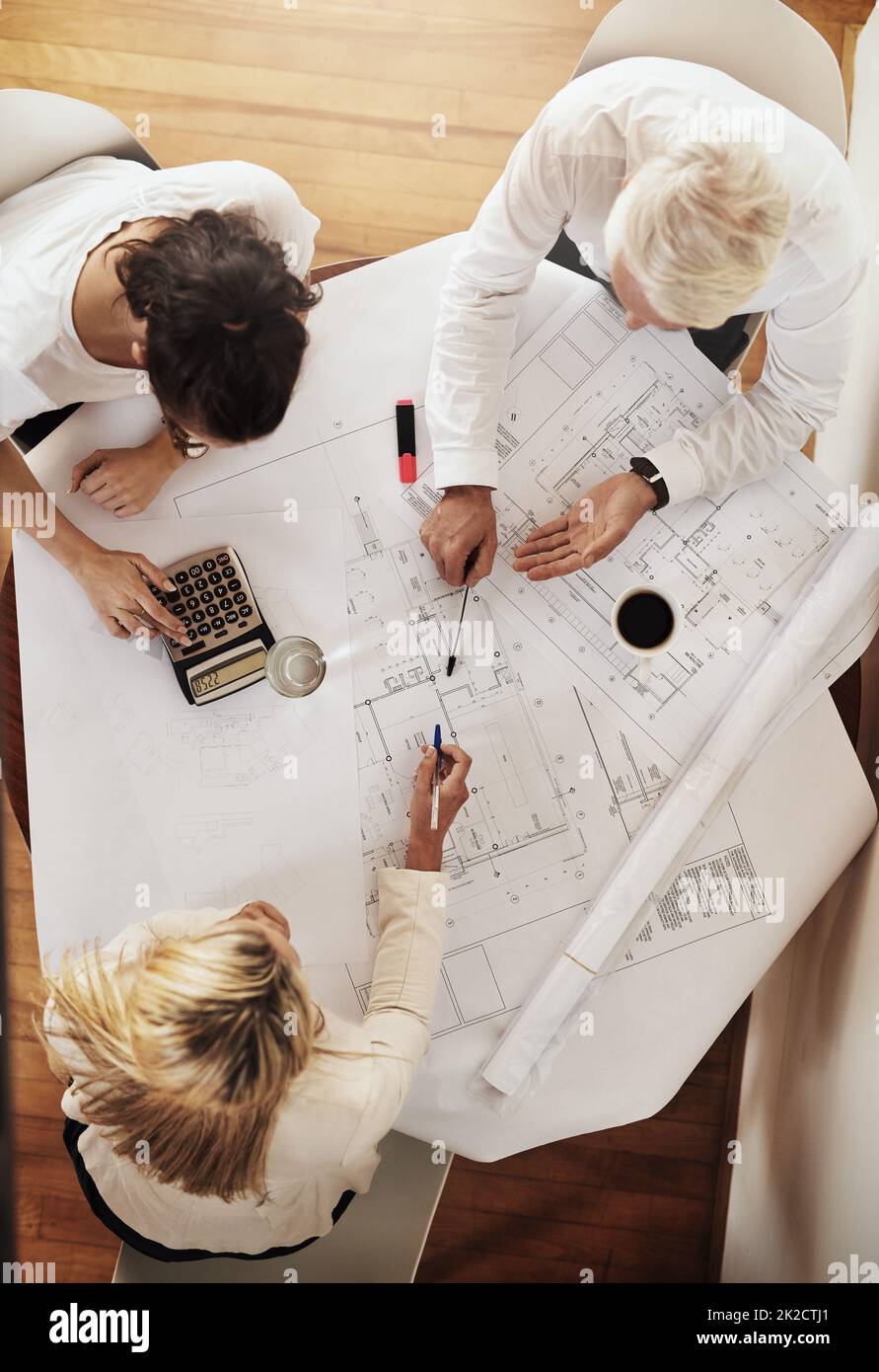 Planning out their next step. High angle shot of a group of architects working together on blueprints of a house around a table inside of a building. Stock Photo