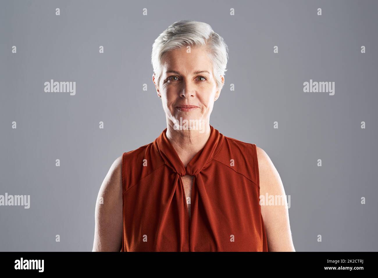 Her beauty is timeless. Portrait of an attractive mature woman posing against a grey background. Stock Photo