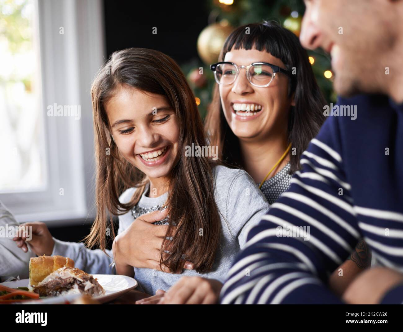 My mom is the funniest. Shot of a little girl sitting on her mothers lap giggling. Stock Photo