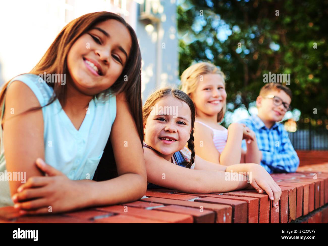 Come hangout with the cool kids. Portrait of a group of young children playing together outside. Stock Photo