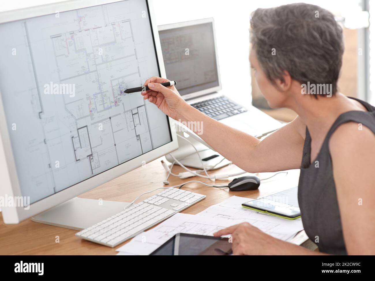 Forward-thinking architecture. A mature female architect working on building plans on her touchscreen computer. Stock Photo
