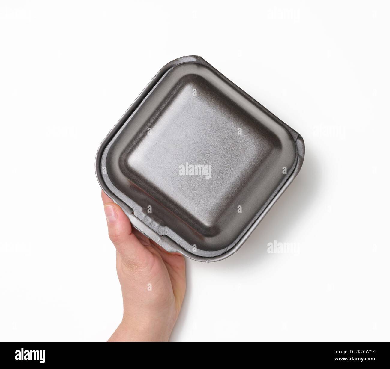 female hand holds a disposable food container. Gray box of polystyrene on a white background Stock Photo