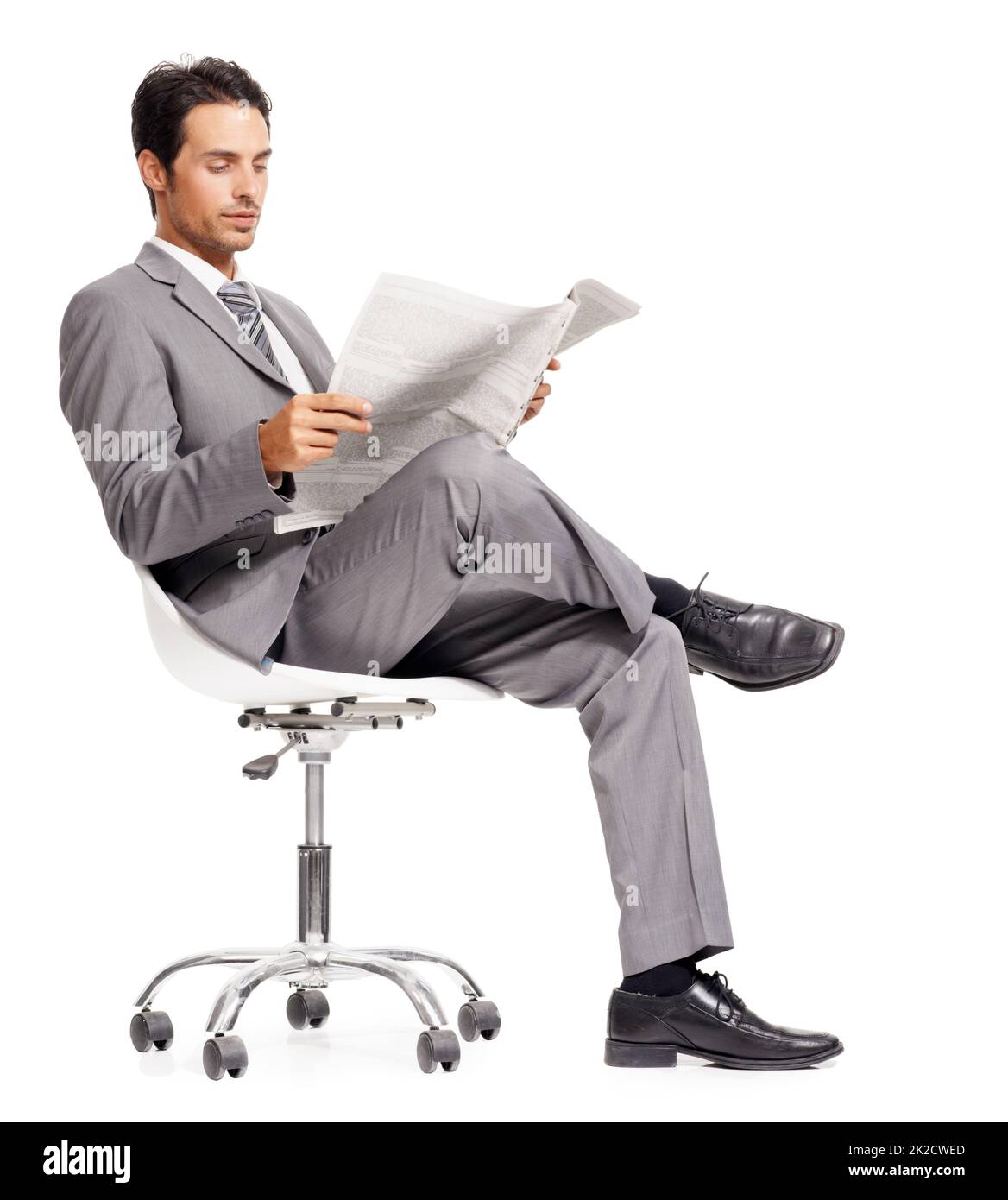 Keeping abreast of the stock market fluctuations. A handsome young executive reading a newspaper while isolated on a white background. Stock Photo