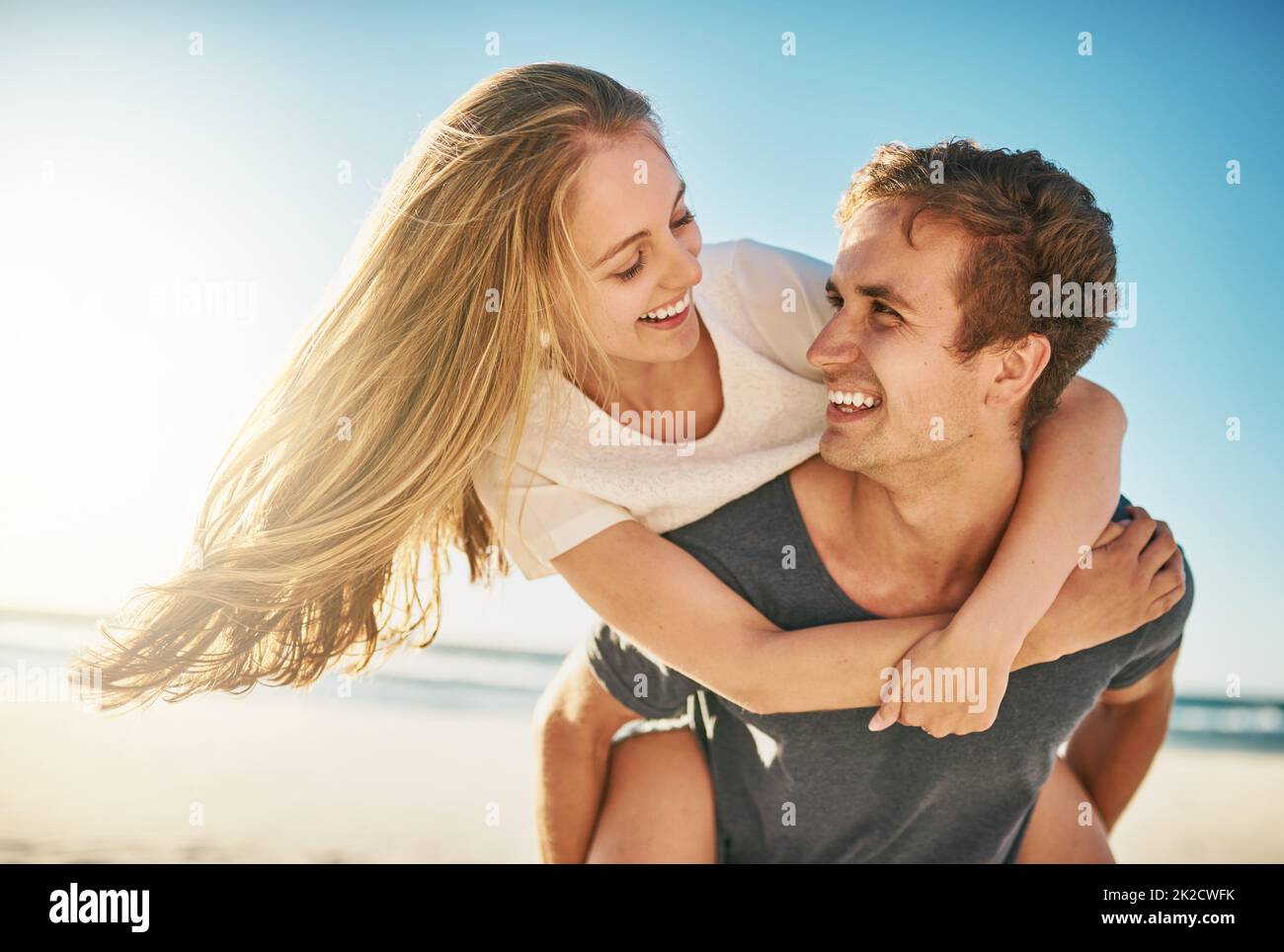 Lovely gay couple on piggyback ride at the beach. Stock Photo