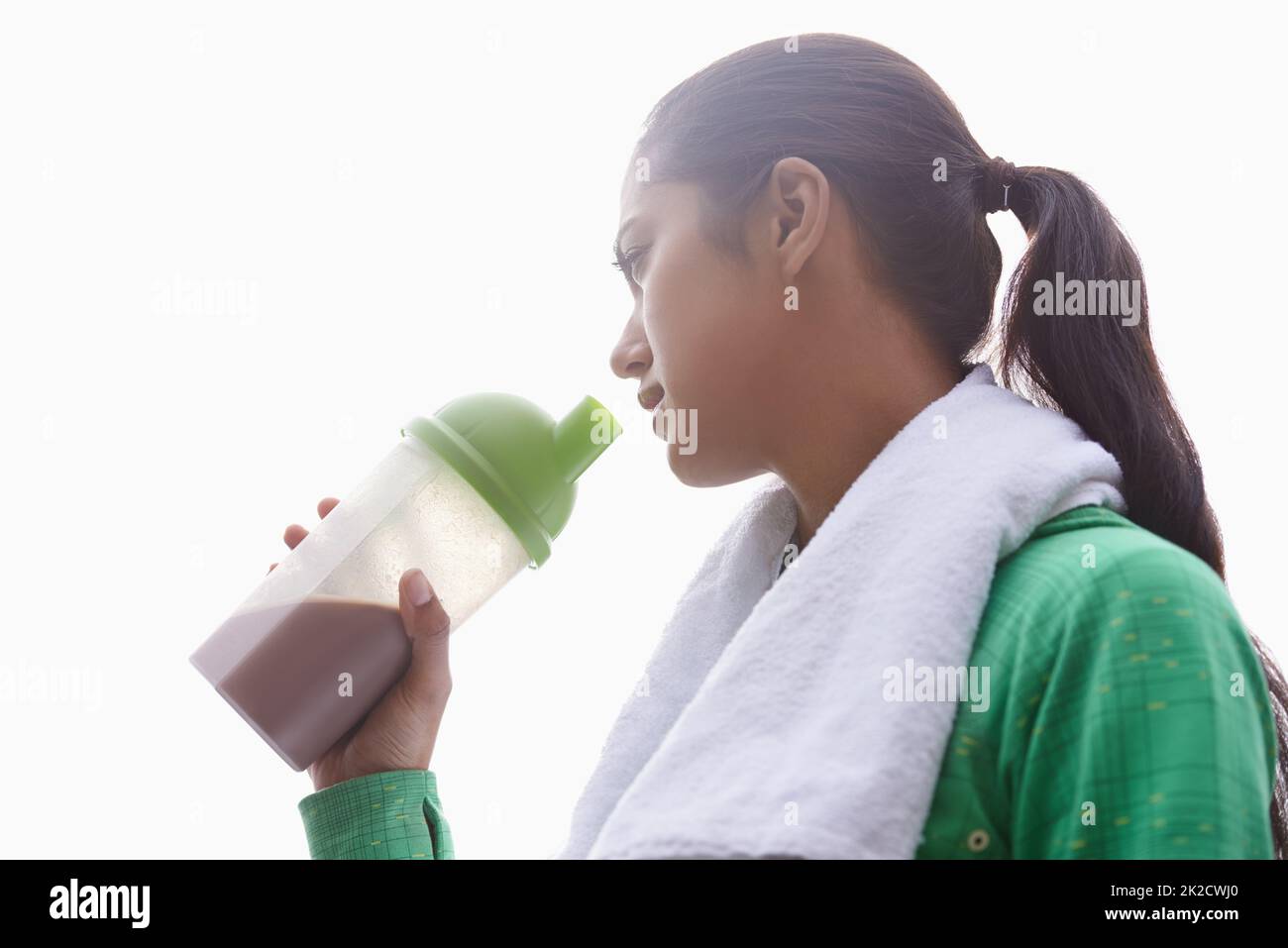 Staying healthy. A young ethnic woman drinking a sports drink outdoors