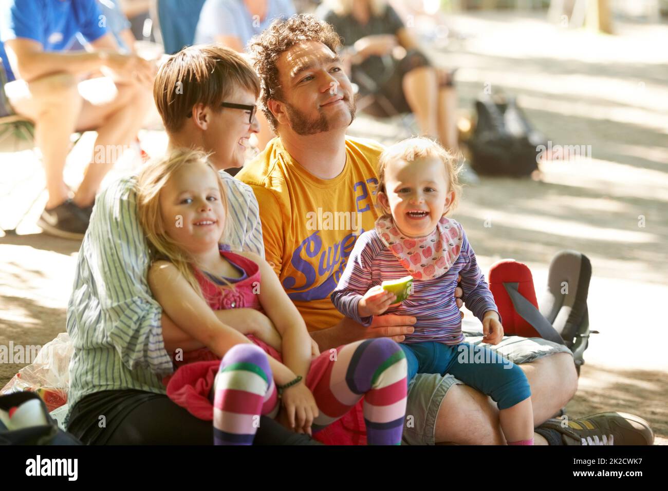 Sitting down to watch the bands. A young family of four sitting down to enjoy the bands at an outdoors music festival. Stock Photo