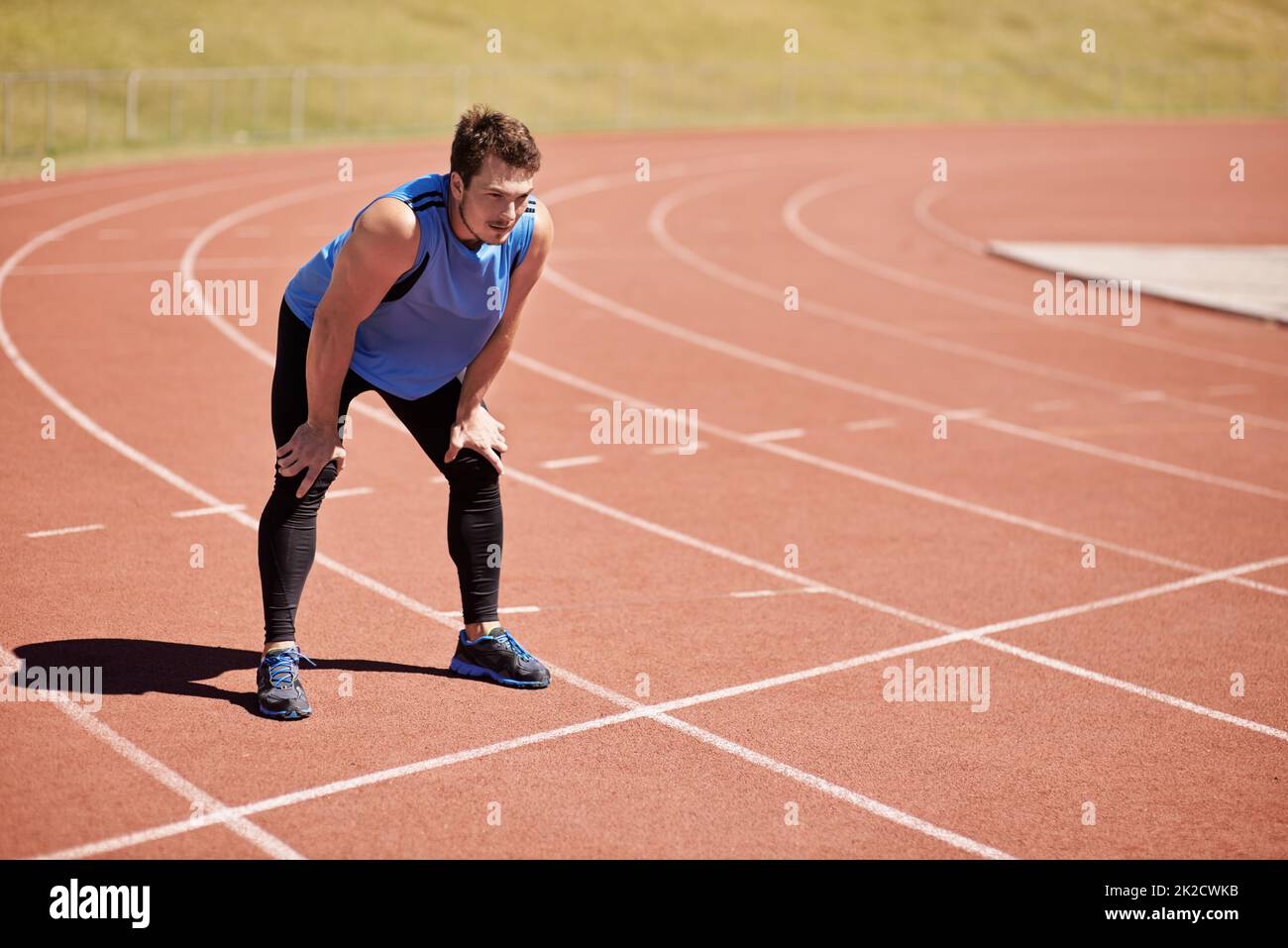 Hes ready to race. Shot of a handsome young runner out on the track. Stock Photo