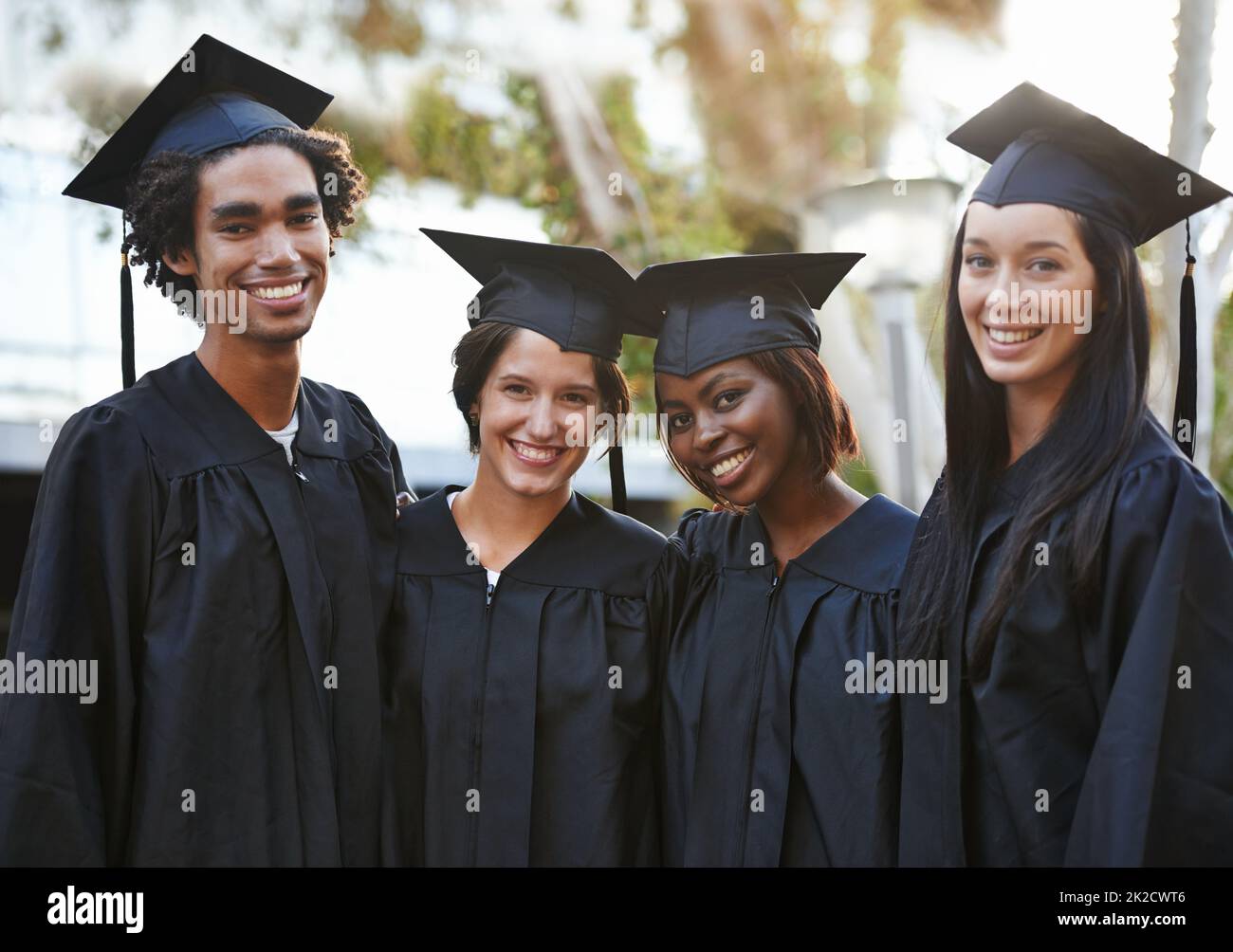 Theyve got a bright future ahead. A group of smiling college graduates standing together in cap and gown. Stock Photo