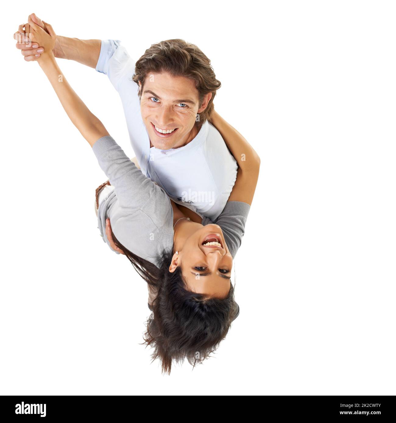 He makes her head spin. A multi-ethnic couple dancing isolated on a white background - high angle view. Stock Photo