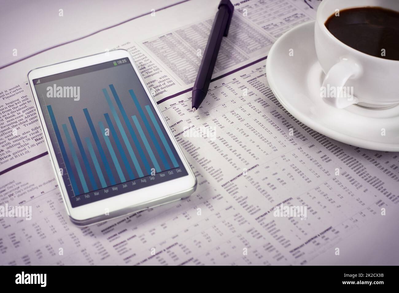 Shot of a smartphone and a cup of coffee on top of the business section of a newspaper. All screen content is designed by us and not copyrighted by others, and upon purchase a user license is granted to the purchaser. A property release can be obtained if Stock Photo