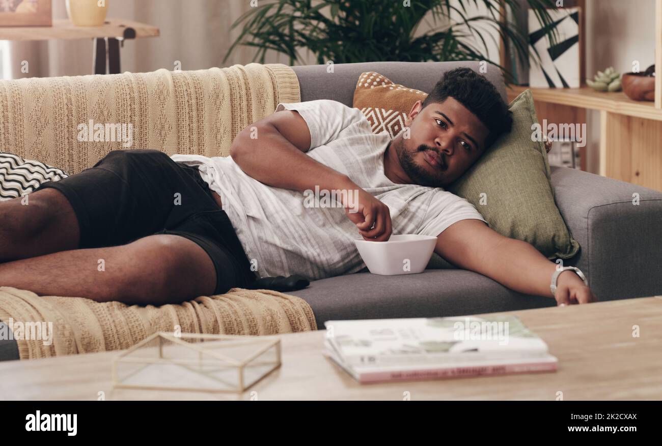 This is a much needed break. Shot of a young man lying on his couch at home. Stock Photo