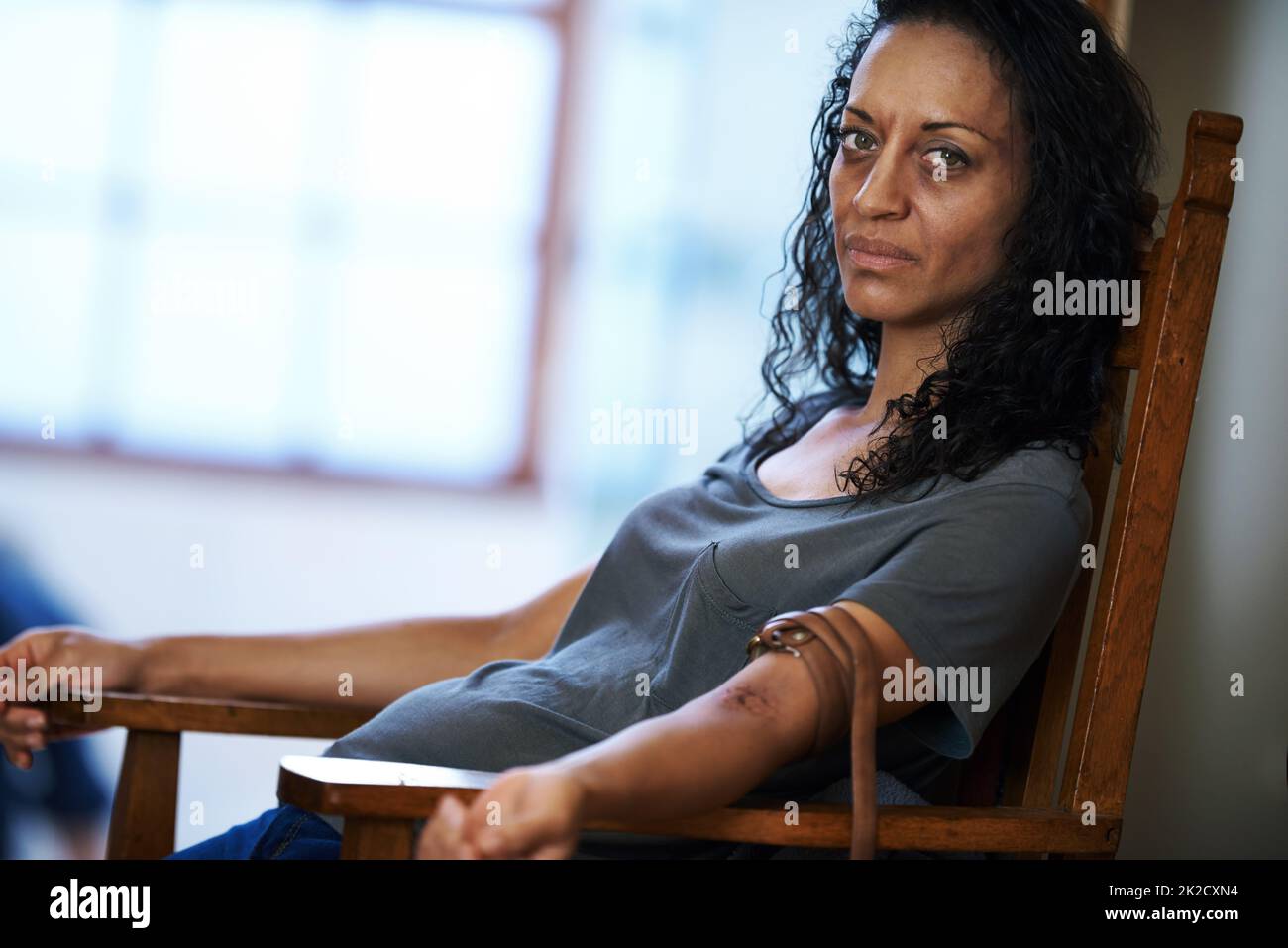 Waiting for change. Portrait of a drug addict sitting in a chair with a belt around her arm. Stock Photo