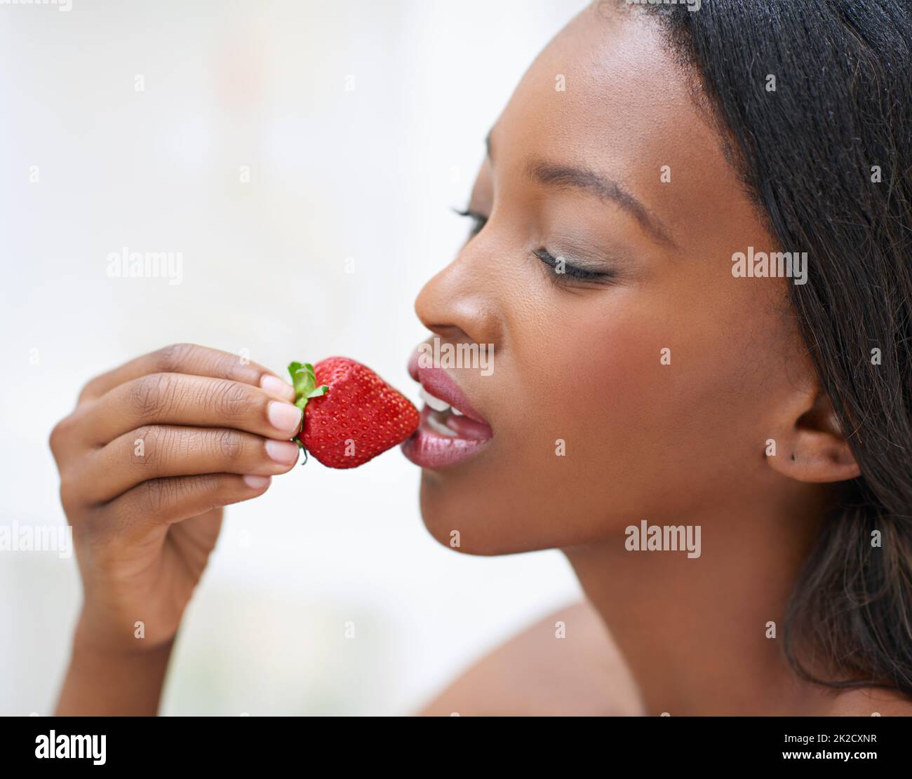 The forbidden fruit. Shot of a beautiful young woman eating strawberries. Stock Photo