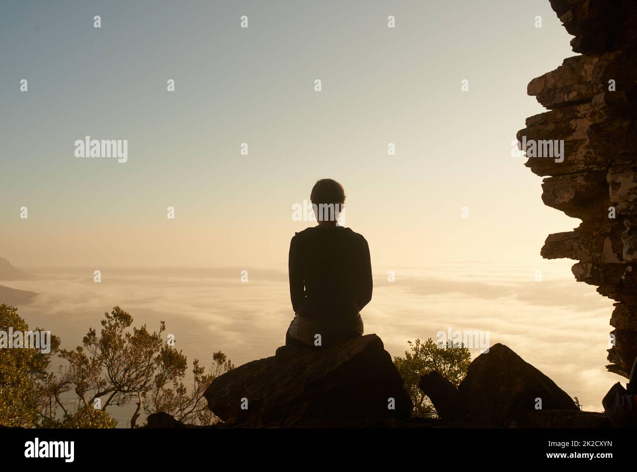 Solitude at sundown. Shot of a woman admiring the view from a mountain top. Stock Photo