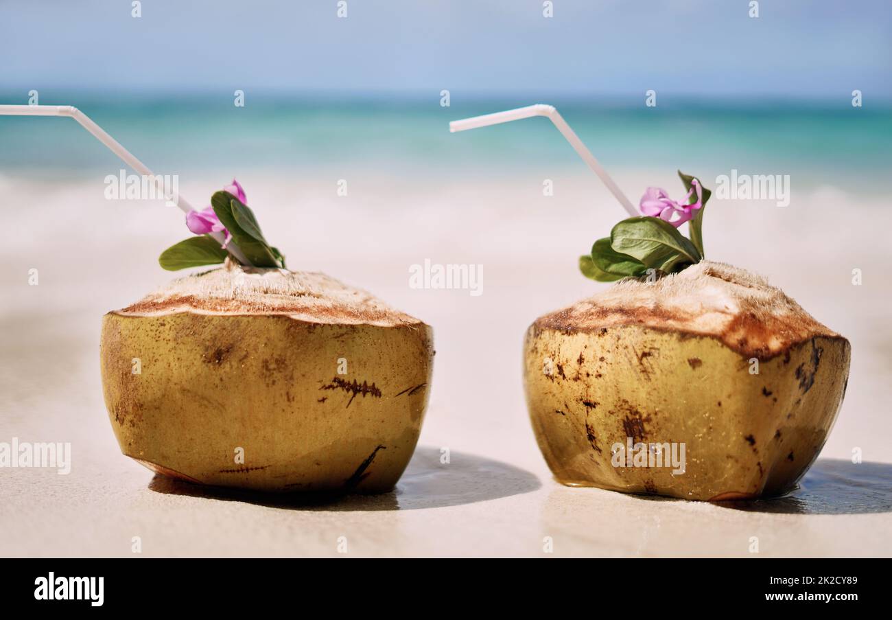 Summer keeps the romance alive. Still life shot of two coconuts placed alongside each other on a beach in Raja Ampat, Indonesia. Stock Photo