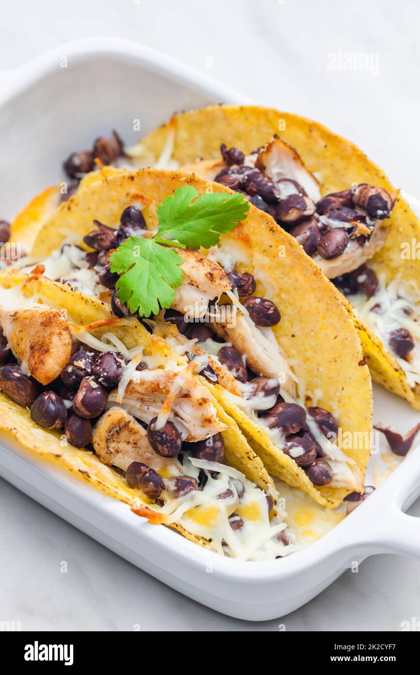 tacos filled with grilled chicken meat, red beans and grated cheese