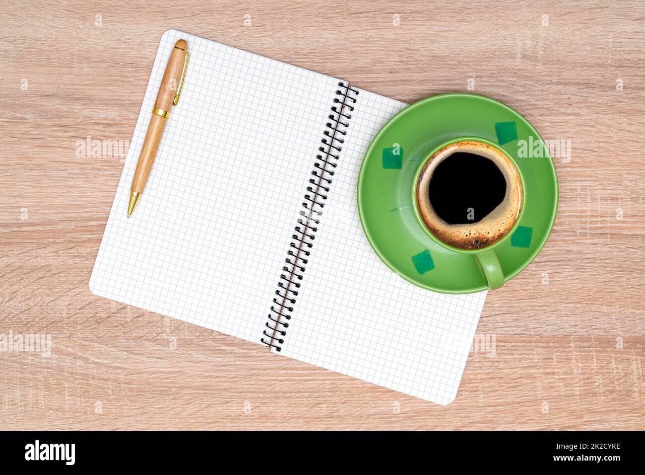 Coffee cup, spiral notebook and pen on the wooden table Stock Photo