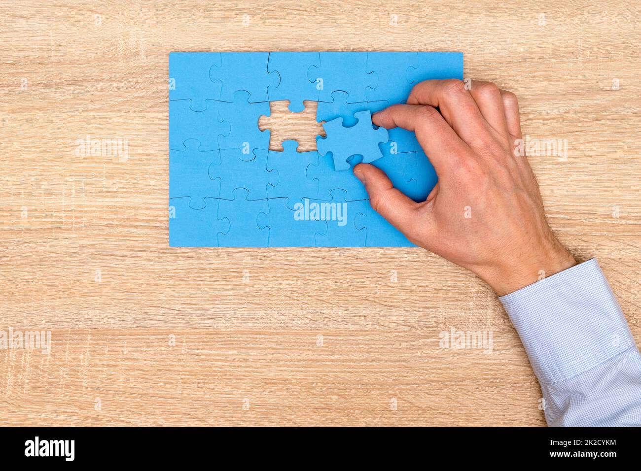 Finishing the last piece of a blue jigsaw puzzle Stock Photo