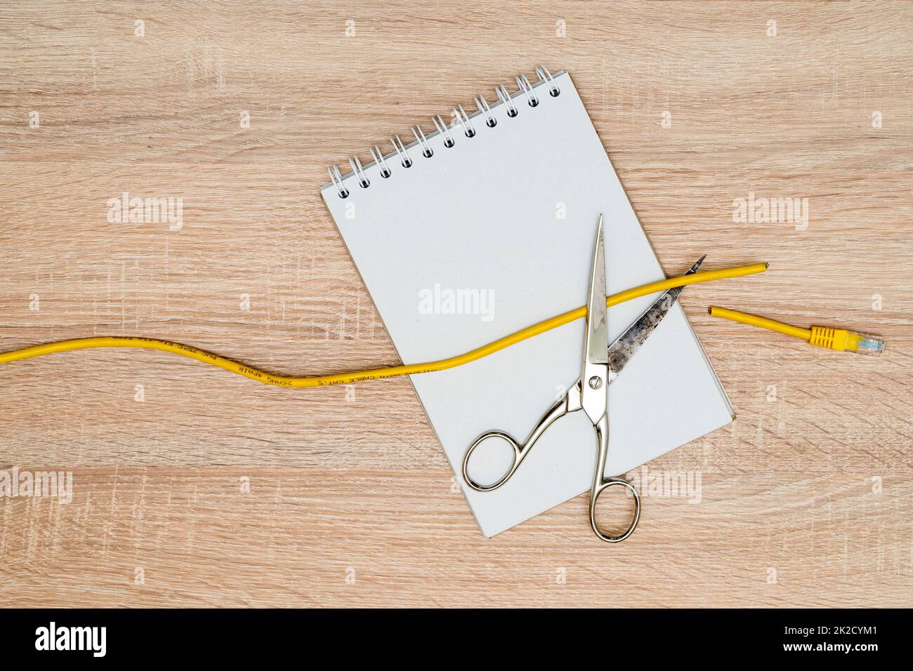 Scissors cutting data cable over a blank spiral notebook Stock Photo