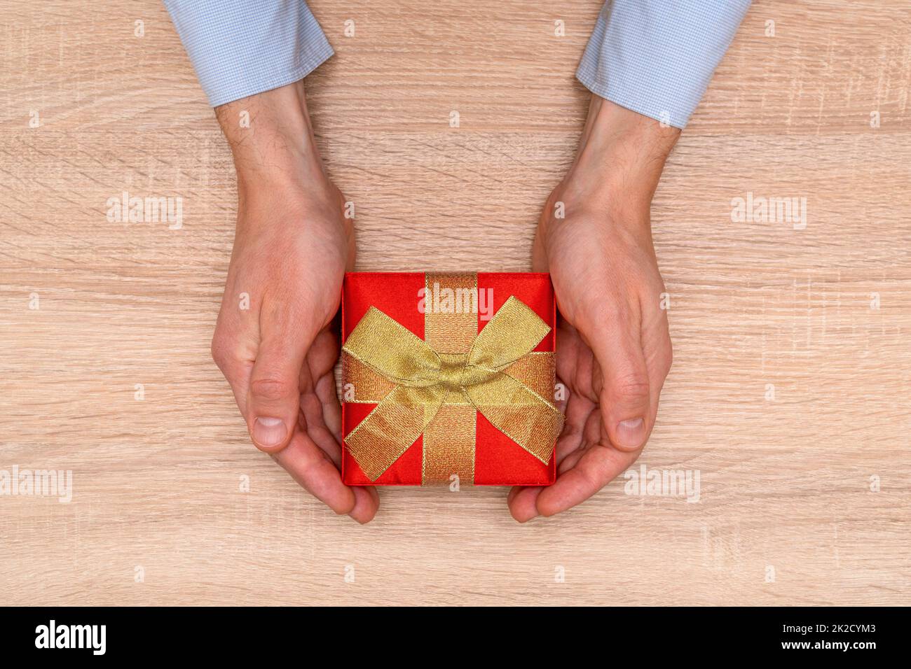 Hands holding gift or present box decorated with gold bow Stock Photo