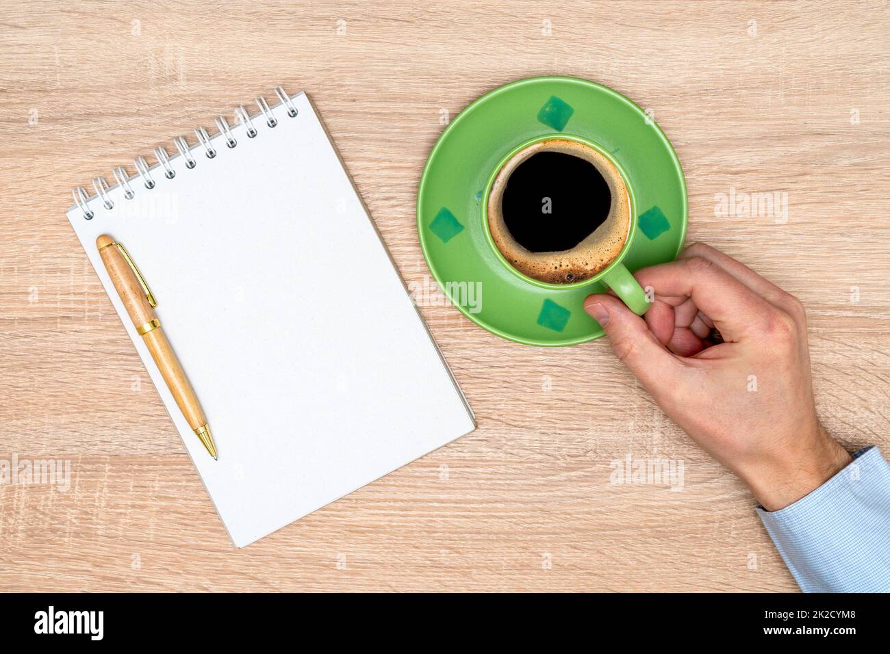 Hand with cup of coffee in the office with notebook Stock Photo