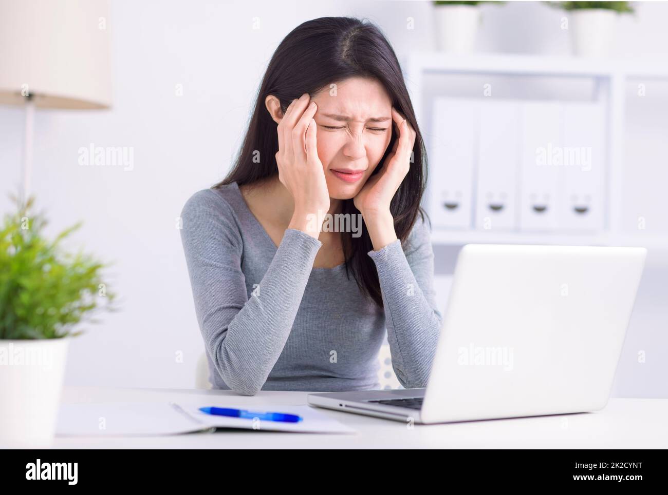 Stressed young  woman suffering from headache after computer work Stock Photo