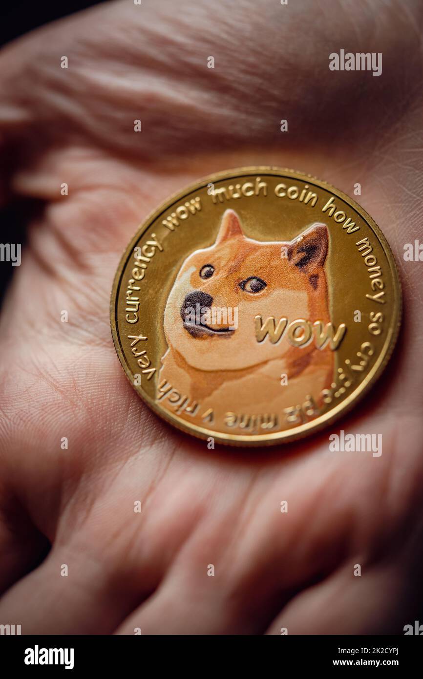 Close up shot of hand holding a gold Dogecoin digital cryptocurrency. Stock Photo