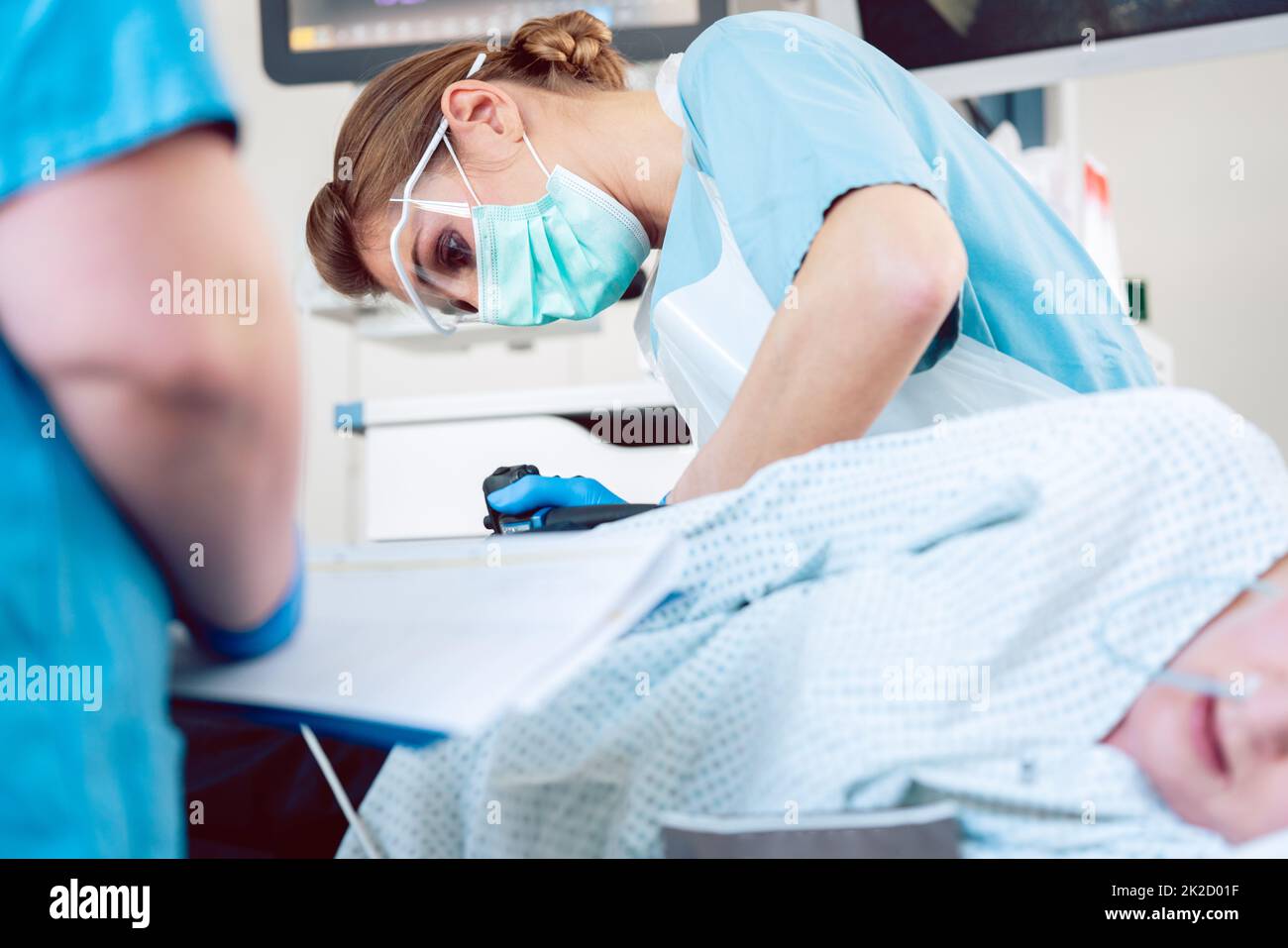 Proctologist during colonoscopy inserting endoscope into patient Stock