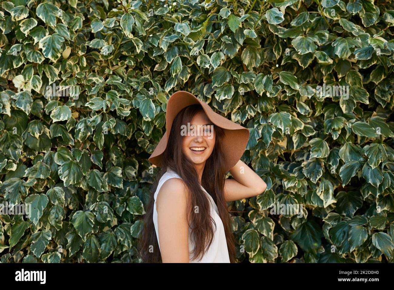 Hats are part of my style. Cropped portrait of a pretty teenage girl standing in front of a large hedge. Stock Photo
